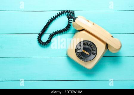 Retro rotary telephone on blue wooden table. Pop culture attributes, top view. Stock Photo