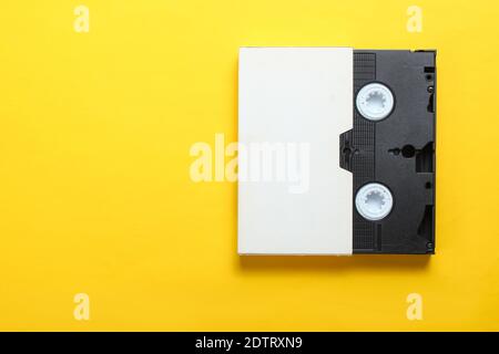 Video cassette in cover, videotape on a yellow background. Top view, minimalism Stock Photo