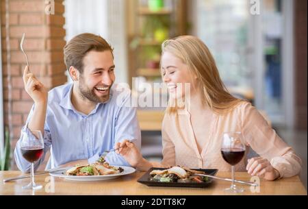 Happy young couple having lunch together at cafe, talking and laughing during meal Stock Photo