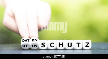 Hand turns dice and changes the German expression "kein Schutz" (no protection) to "Datenschutz" (data privacy). Stock Photo