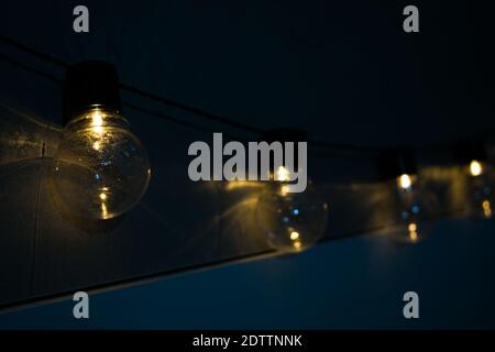 Decoration of lit light bulbs hanging in a dark room Stock Photo