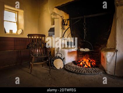 The wooden chair in the old style antique vintage kitchen with tools and fireplace for cooking Stock Photo