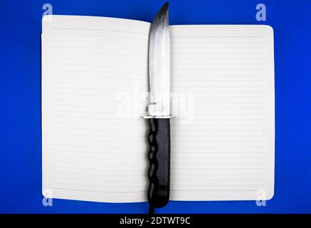 Opened Book with a Knife on the Blue Paper Background Stock Photo