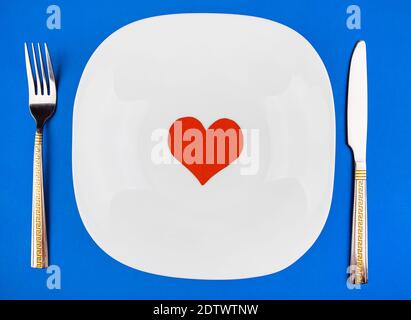Plate with a Cutlery and a Heart Shape on the Blue Paper Background Stock Photo