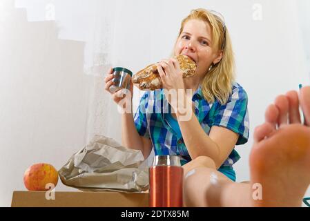 Woman painter have lunch at the facility, home repairman has lunch after working in domestic house, Stock Photo