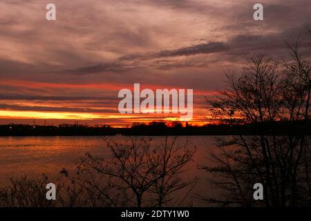 Dramatic sky over the water. View on a lake at sunsetbor sunrise. Silhouette of vegetations in the foreground. Stock Photo