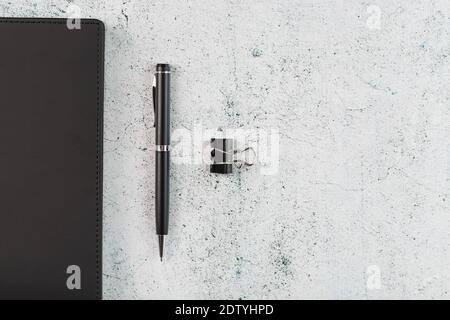 Black Notepad with a black pen on a gray background. Top view, minimalistic concept. Free space. Stock Photo