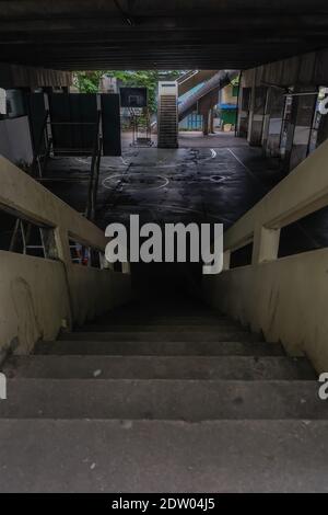 View from the top of the old cement stairs leading down to the community basketball court under the bridge. Focus and blur. Stock Photo