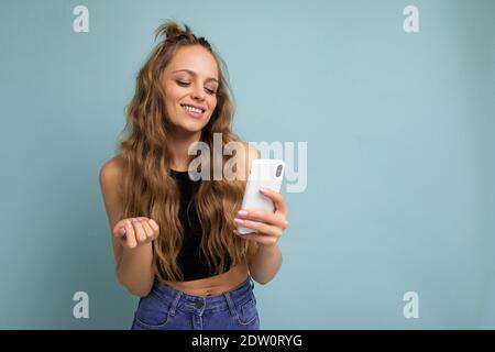 Positive smiling beautiful good looking young woman wearing casual stylish outfit poising isolated on background with empty space holding in hand and Stock Photo