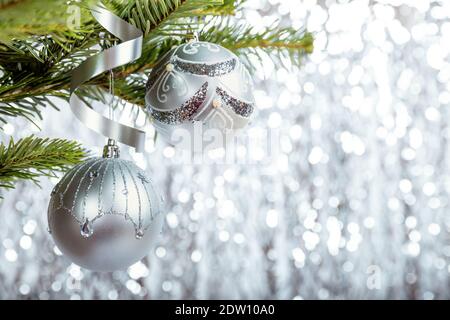 Christmas tree branch decorated with silver Christmas balls on a shiny background Stock Photo