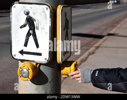 A woman activates a pedestrian crossing signal at a crosswalk at an intersection in Santa Fe, New Mexico. Stock Photo