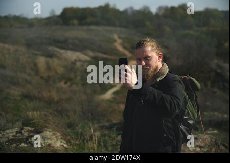 Hiker using compass on smart phone in forest. Walkway on background Stock Photo