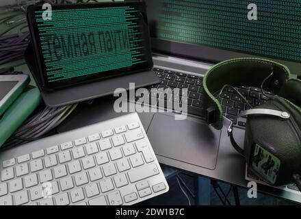 Binary codes on the screens of the computer and tablette, a headphone as well. Russian script meaning "cyber attack".. Stock Photo