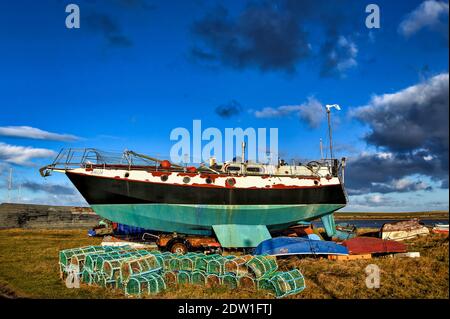 Abandoned yacht dry docked at the harbor on Lindisfarne Island in Northumberland Stock Photo