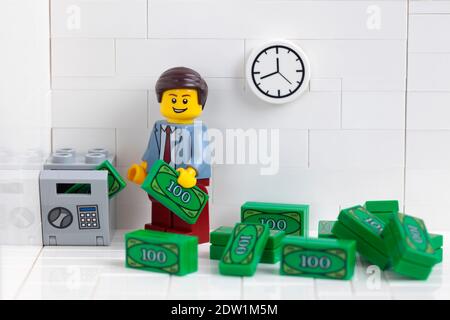 Tambov, Russian Federation - December 22, 2020 Lego businessperson minifigure putting money into a safe that is in his office. Stock Photo