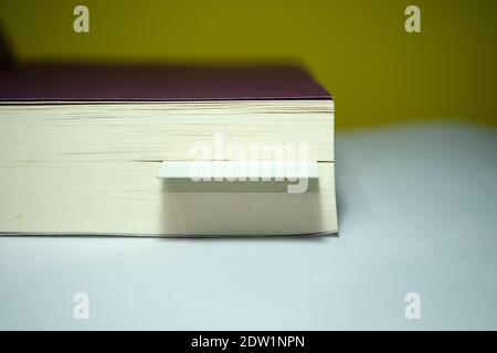 A corner of the thick book and bookmark inside the book. Isolated background and close up photo. Stock Photo