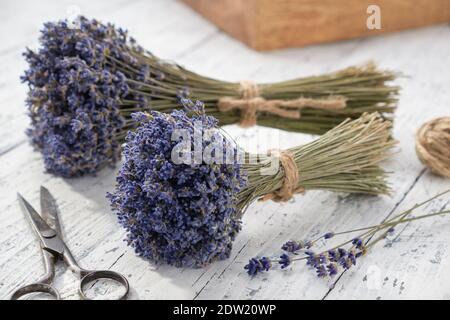 Dry lavender flower bouquets, scissors and wooden box on white table. Stock Photo
