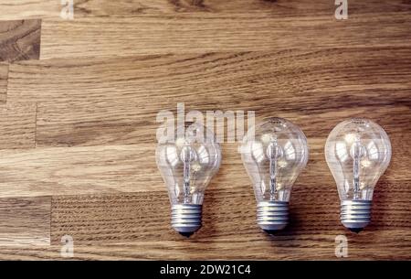 Three light bulbs on wooden table. Concept for idea, thinking, problem solving Stock Photo