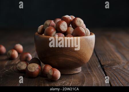 Wooden bowl of hazelnuts on dark wooden table. Stock Photo
