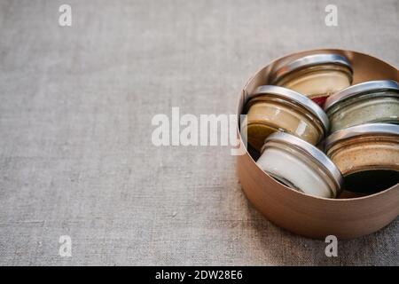 Nuts and seeds butter in glass jars on natural fabric background with copyspace. Homemade raw organic peanut, almond, coconut, hemp seeds, pumpkin Stock Photo