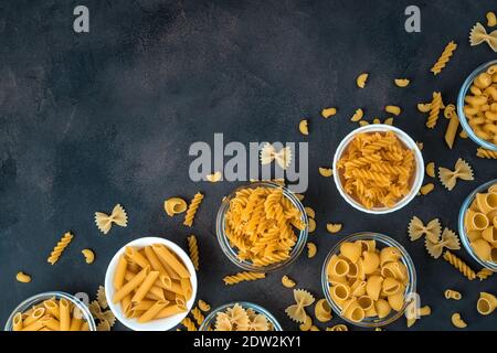 Pasta of various types in bowls on a dark concrete background. Stock Photo