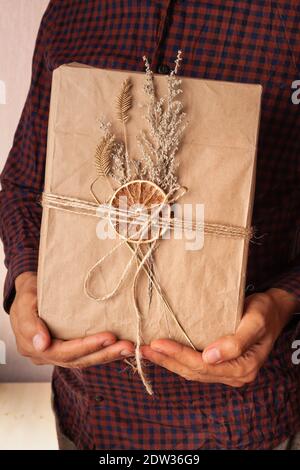 Handmade gift box packed in craft paper decorated with dried flowers. Stock Photo