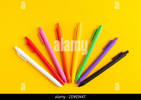 Multi-colored pens on a yellow background. The concept of the beginning of the school year, office and school supplies. Stock Photo