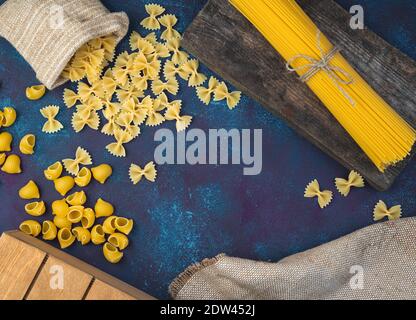 Different varieties of pasta on a blue concrete background. Stock Photo