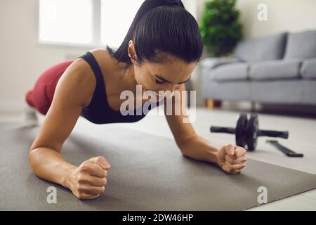 Happy smiling young woman holding a plank position during a fitness workout at home Stock Photo