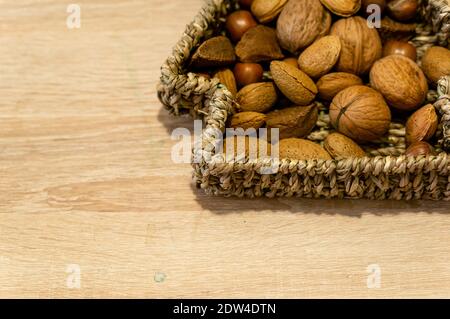 A horizontal shot of mixed nuts in a woven basket on the table Stock Photo