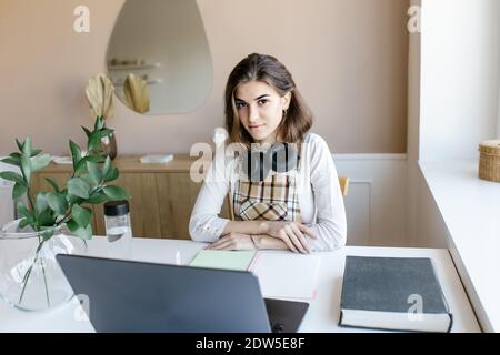 Attractive girl wearing headphones study with internet chat skype teacher prepare for exam, girl school student learning online, watch webinar looking Stock Photo