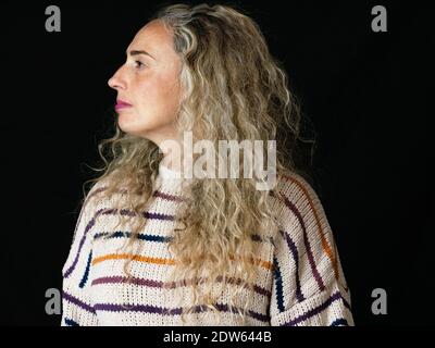 A closeup shot of a beautiful blonde curly-haired female on the black background Stock Photo