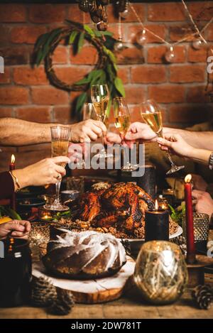 Family or friends celebrating Christmas or New Year together. Peoples hands making cheers with glasses of champagne over holiday party rustic wooden t Stock Photo