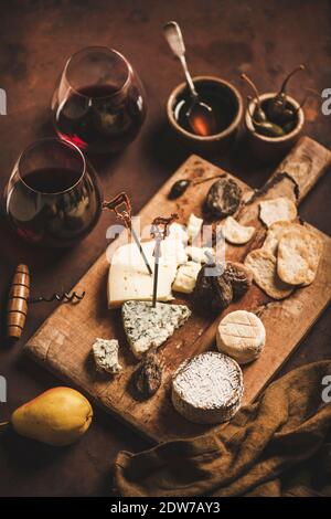 Cheese and Fruits Assortment on Cutting Board with Red, White Wine on  Wooden Background. Stock Photo by annapustynnikova