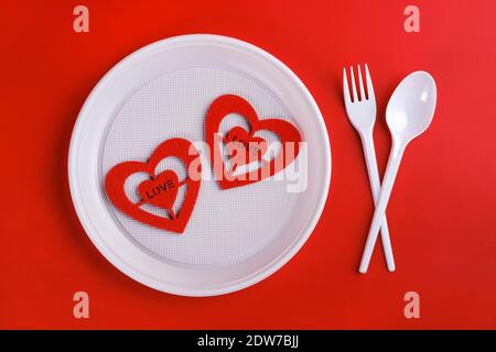 Top view of plastic white disposable fork, spoon, plate and red hearts isolated  Stock Photo