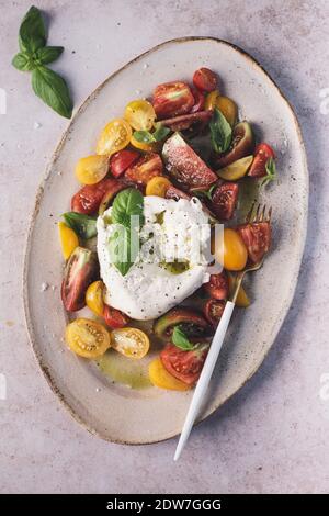 Heirloom tomato salad with burrata and olive oil on light background. Stock Photo