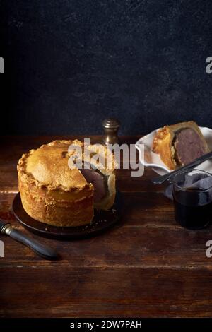 Traditional british raised pork pie with bacon and herbs Stock Photo