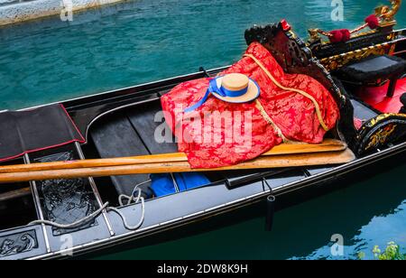 Close up of an empty Venetian gondola with hat, oars and blanket visible in Venice, Italy Stock Photo