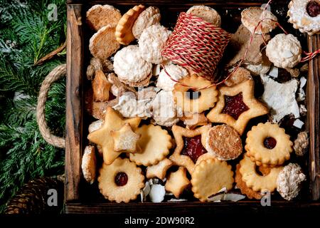Christmas Homemade shortbread biscuits cookies collection different shapes, include traditional Linz biscuits with red jam in wooden tray over thuja b Stock Photo