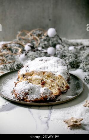 Traditional homemade german Christmas baking stollen cake bread on plate with silver xmas decorations over white marble background. Stock Photo