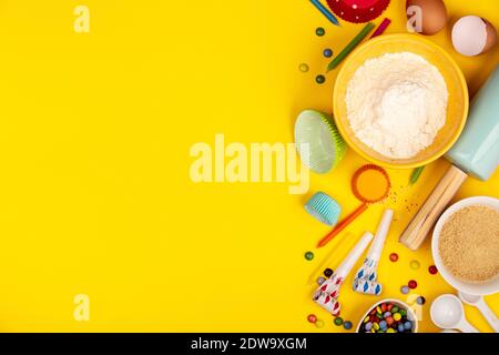 Baking birthday cupcakes background frame. Ingredients, kitchen items for baking, candles. Kitchen utensils, flour, eggs, sugar. Text space, top view. Stock Photo