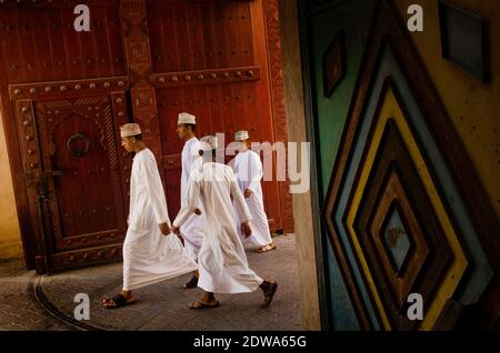 A group of young Omani men seen wearing traditional clothes, Nizwa souk, Oman.Often overlooked as a potential travel destination and yet its rich history and centuries old culture that has so much to offer. Oman is an incredibly diverse landscape of tropical palm fringed wades, remote deserts and green terraced mountains, thriving Souks and one of the most welcoming people of the Arabian Gulf region and must deserve further attention. Stock Photo