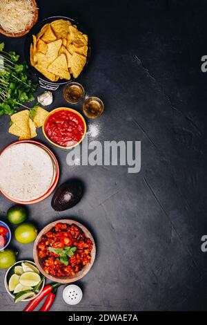 Concept of Mexican food (corn tortillas, nachos, salsa, avocado, limes, cheese, chili con carne) flat lay Stock Photo