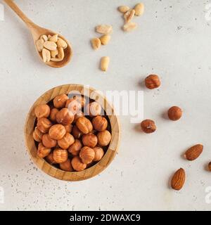 Hazelnuts in a wooden bowl, salted peanuts in a wooden spoon. The concept of healthy eating. Nuts. Stock Photo