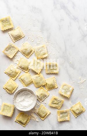 Homemade Ravioli and a little bowl of flour on a marble surface Stock Photo