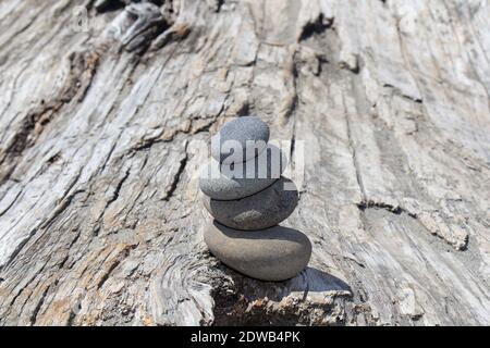 A Cairn Of Four Smooth Stones Balanced Atop A Large Driftwood Log In La Push, Washington, Usa.