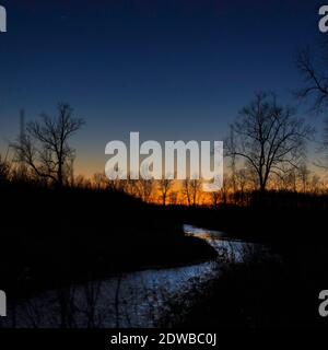 The December 2020 planetary conjunction between Jupiter and Saturn seen with the colors of sunset over a brushy creek in Jackson County, IN, USA. Stock Photo