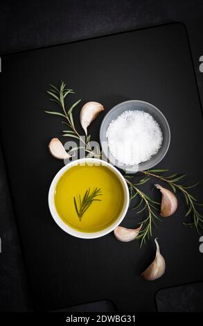 Olive oil, salt flakes, garlic cloves and rosemary. Stock Photo