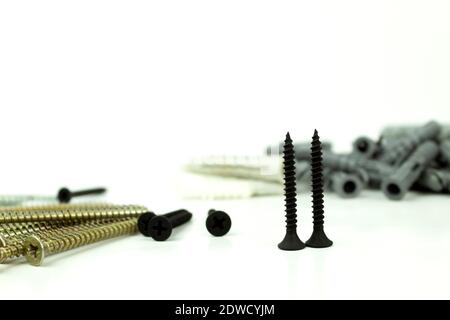 Construction screws and dowels on an isolated white background. Old screws and dowels are in a row. White background Stock Photo