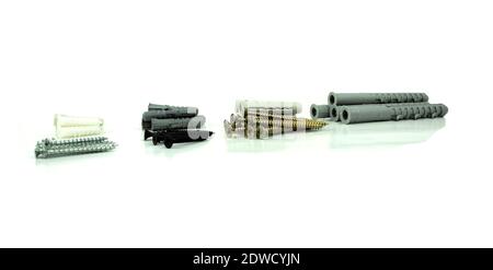Construction screws and dowels on an isolated white background. Old screws and dowels are in a row. White background Stock Photo